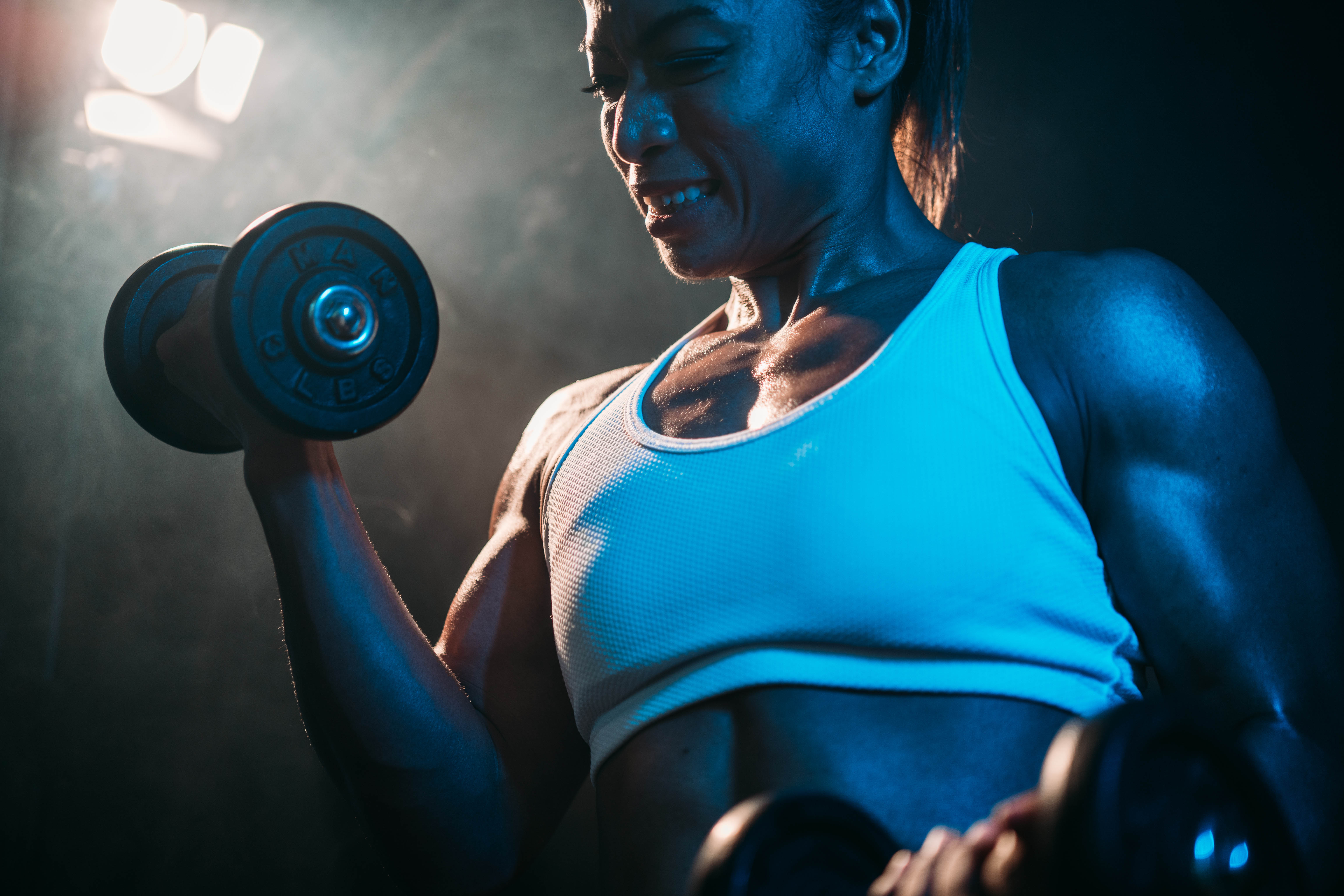 Female weightlifter and bodybuilder lifting a heavy weight and showing off her muscles Female weightlifter and bodybuilder lifting a heavy weight and showing off her muscles